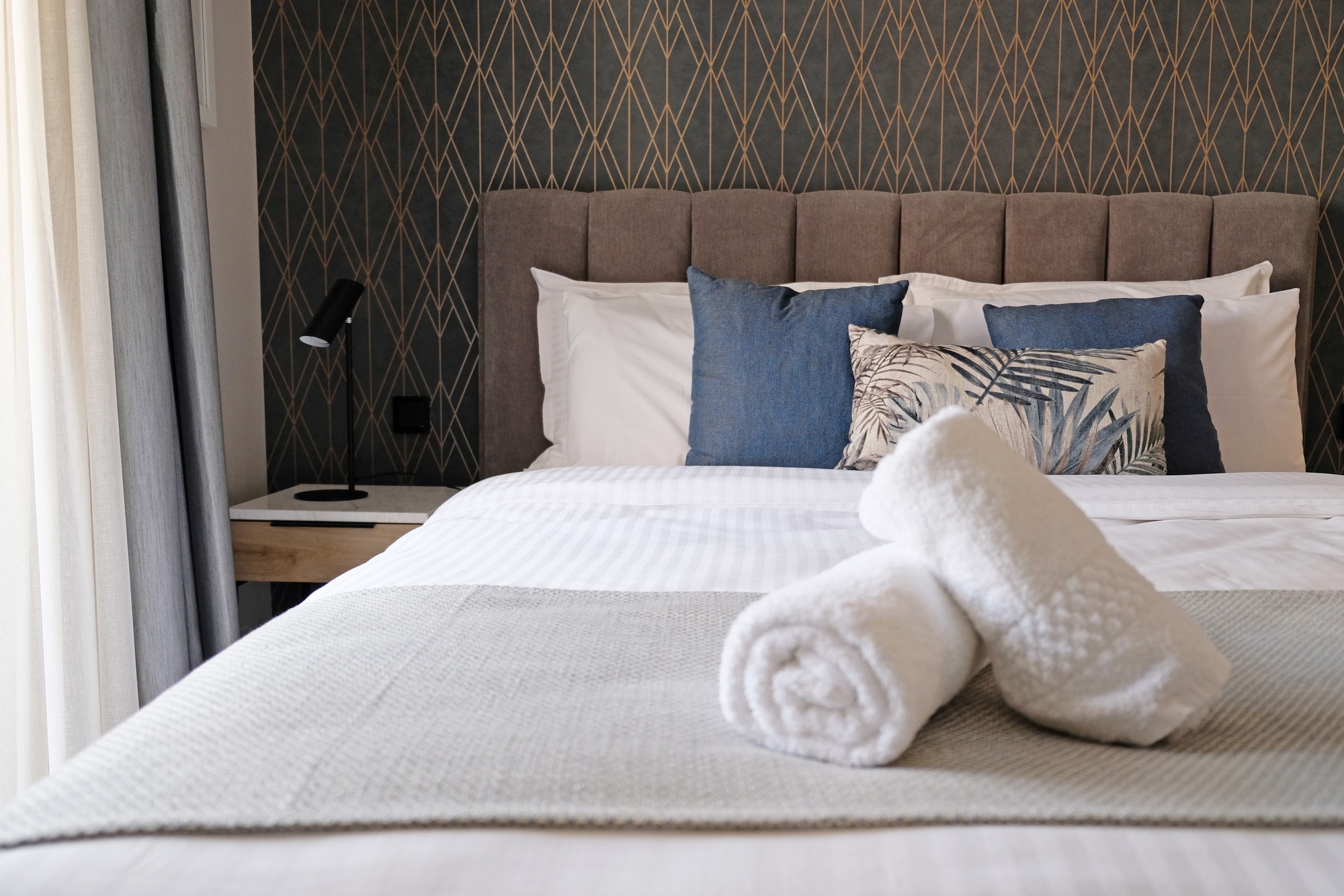 View of comfortable bed with towels in hotel bedroom decoration in cozy style.